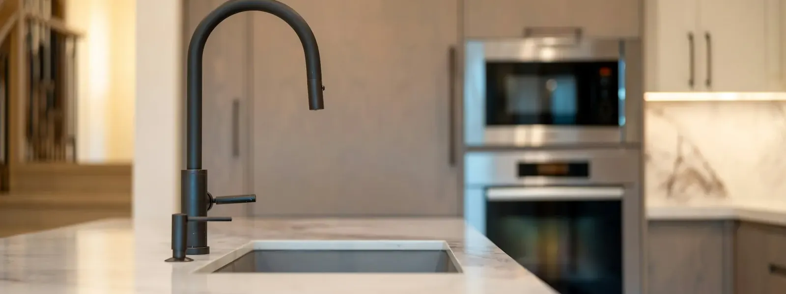 Bright modern kitchen with a matte black faucet over a white stone counter