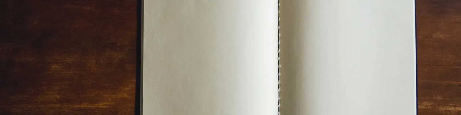 Open blank notebook on a dark wooden desk