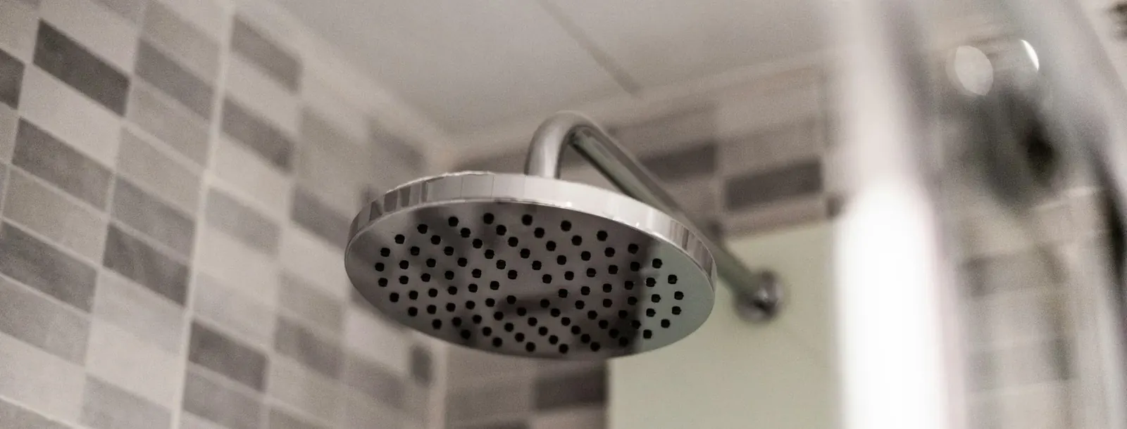 Rain shower head with water falling in a bright bathroom