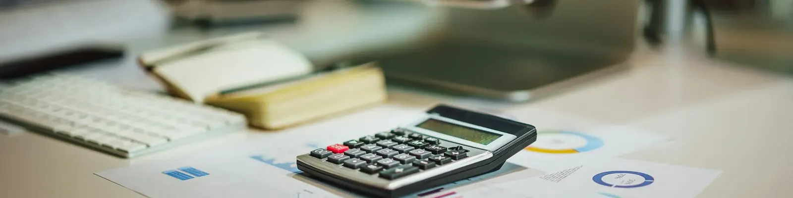 Desk with documents, a calculator and a laptop