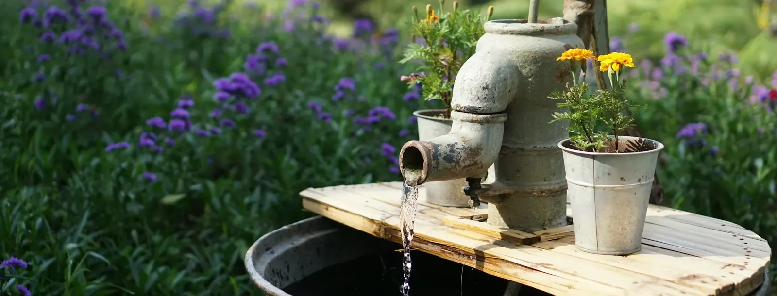 Vintage hand pump beside a garden planter